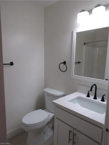 Bathroom featuring a white vanity with an integrated sink, a light-toned countertop, and matte black fixtures