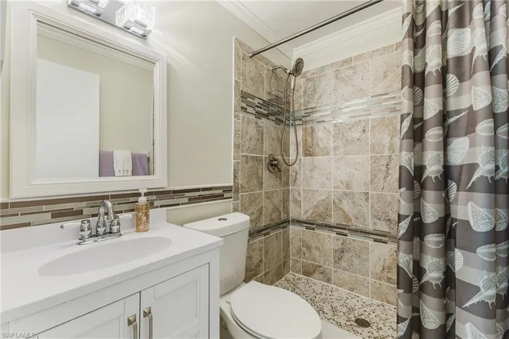 Full bath with a shower stall, tasteful backsplash, ornamental molding, and vanity