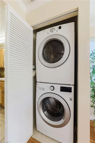 Laundry area with crown molding and stacked washing machine and dryer