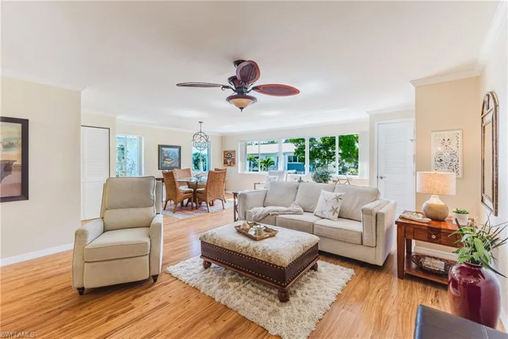 Living room featuring light wood-style flooring, ceiling fan, and ornamental molding