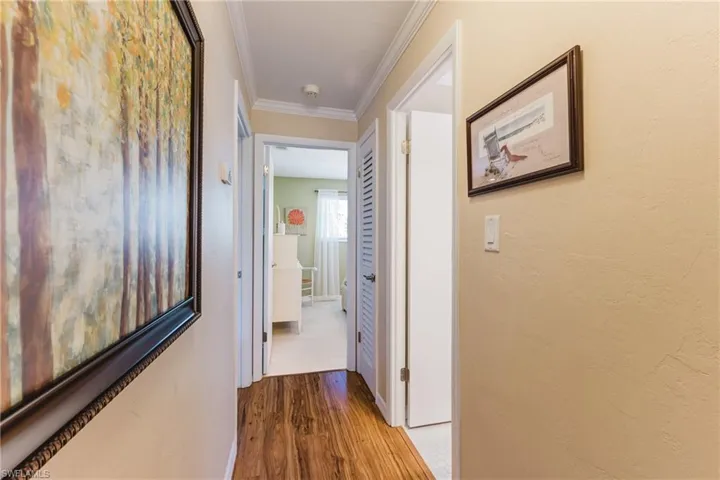 Hallway with crown molding and wood finished floors