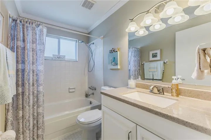 Full bathroom featuring vanity, shower / bath combo with shower curtain, and crown molding