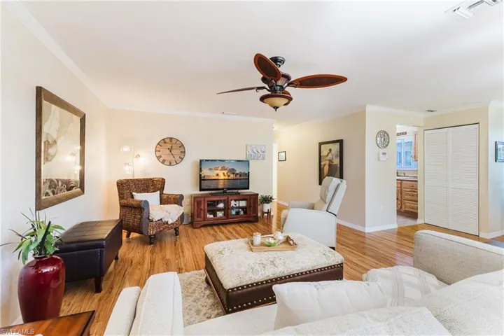 Living room with crown molding, a ceiling fan, and light wood-style flooring