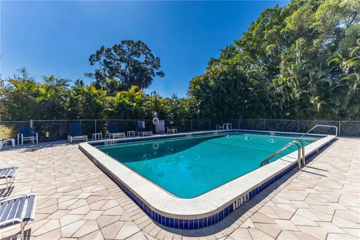 Community pool featuring a patio and view of wooded area