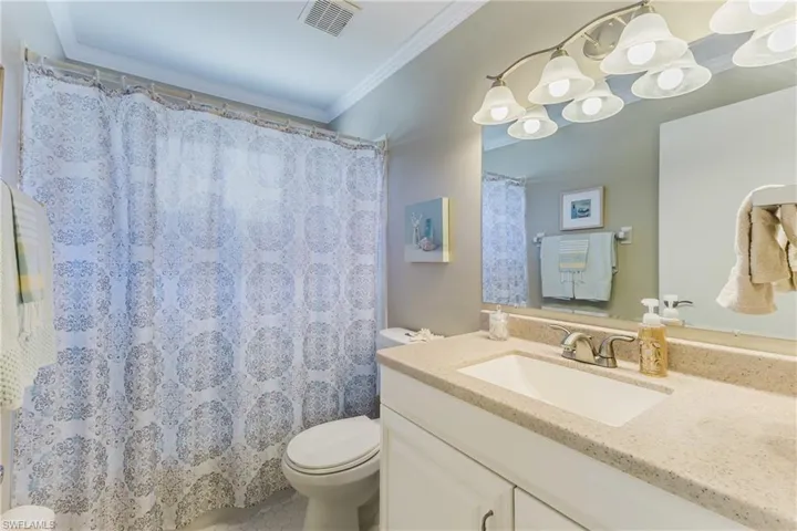 Full bathroom featuring vanity, a shower with shower curtain, and crown molding