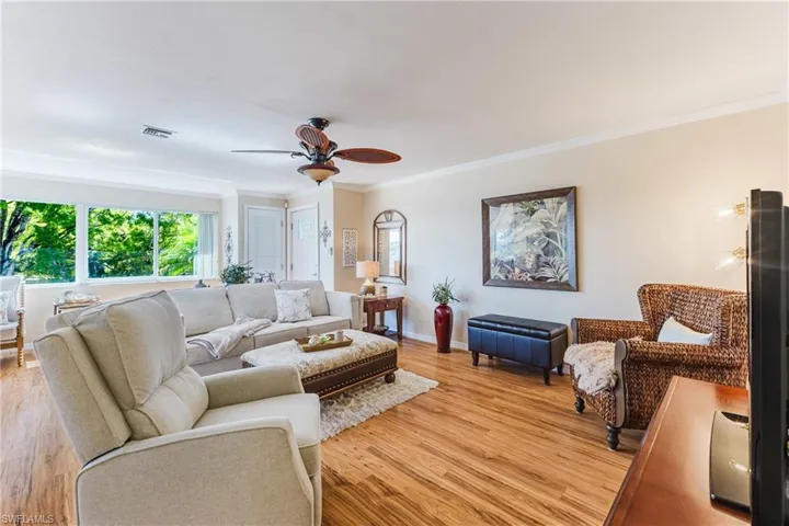 Living area with ceiling fan, crown molding, and light wood-style flooring
