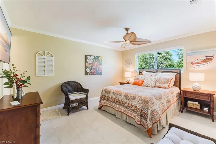 Bedroom with ornamental molding, a ceiling fan, and tile patterned floors