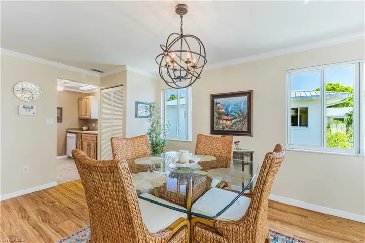 Dining area with light wood-style flooring, a chandelier, ornamental molding, and ceiling fan