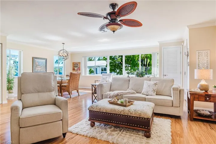 Living area featuring light wood-style floors, crown molding, ceiling fan, and suspended lighting