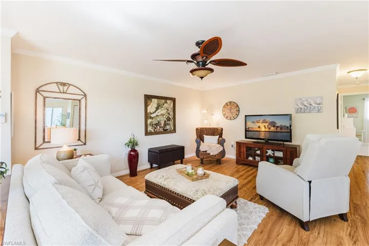 Living room featuring light wood-type flooring, crown molding, and ceiling fan