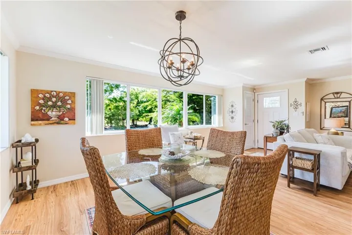Dining space featuring light wood finished floors, crown molding, and hanging lights