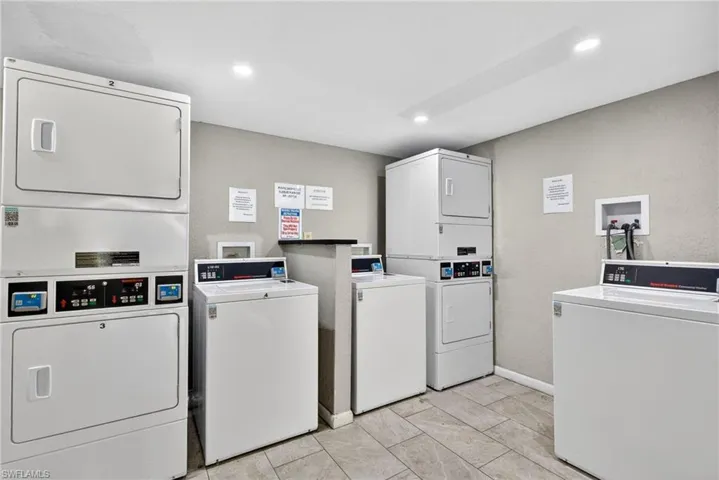 Communal laundry room featuring stacked washer / dryer, a textured wall, and recessed lighting