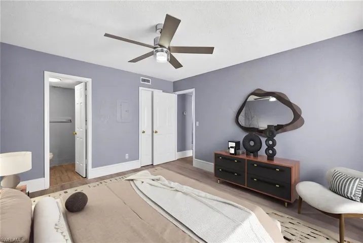 Bedroom with a ceiling fan, light wood-style floors, ensuite bath, and a textured ceiling