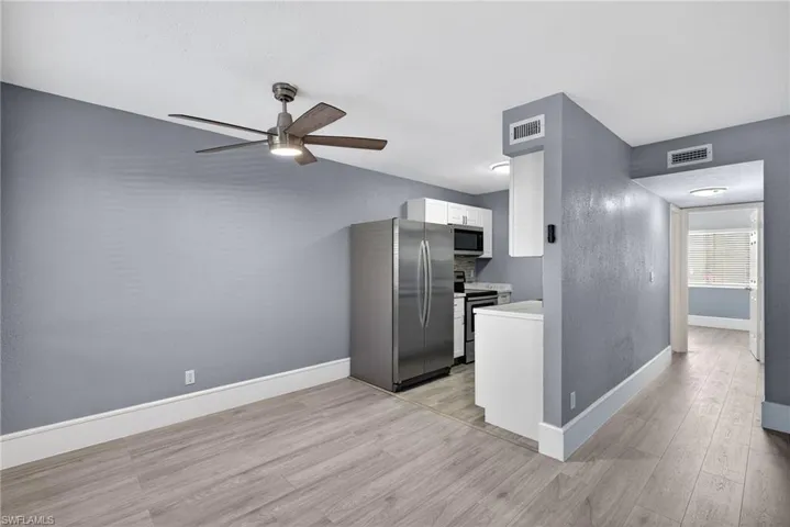 Kitchen featuring stainless steel appliances, white cabinets, light wood-style floors, light countertops, and ceiling fan