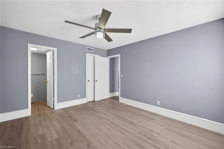 Unfurnished bedroom with light wood-type flooring, a ceiling fan, a textured ceiling, and ensuite bath