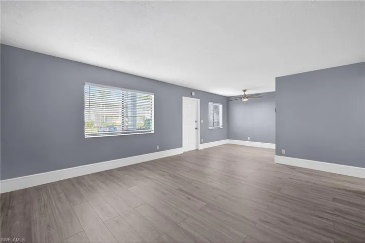 Unfurnished room with a textured ceiling, dark wood-style floors, and a ceiling fan