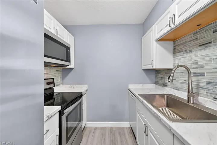 Kitchen with stainless steel appliances, white cabinets, tasteful backsplash, and a textured ceiling