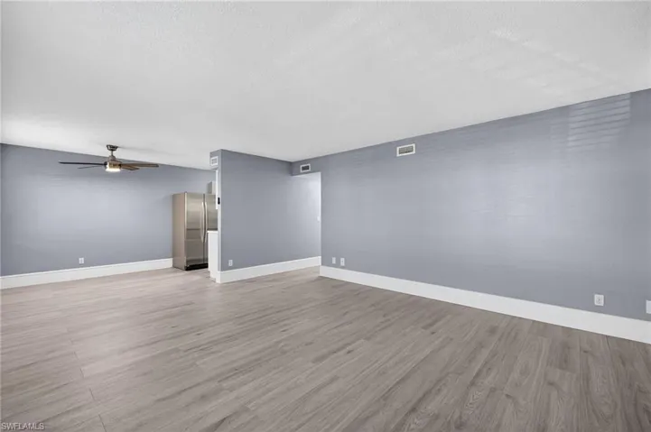 Below grade area featuring light wood finished floors, freestanding refrigerator, ceiling fan, and a textured ceiling