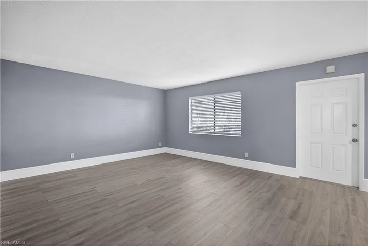 Unfurnished room featuring dark wood-type flooring and baseboards