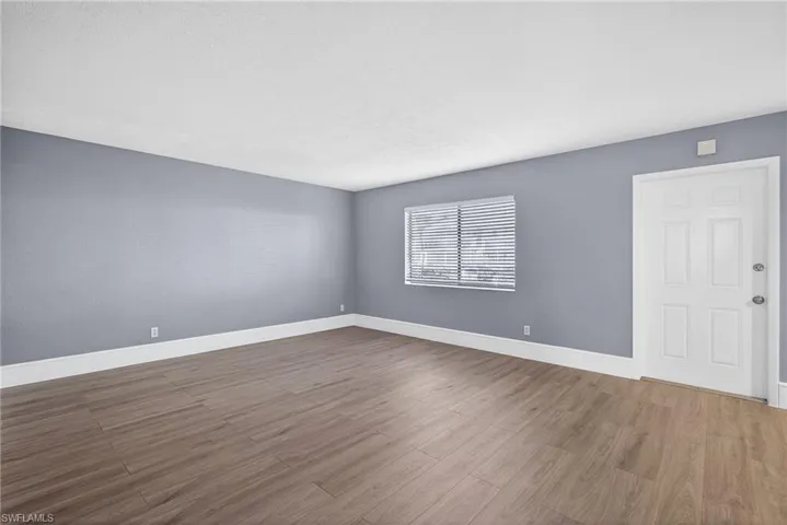 Empty room with baseboards and dark wood-type flooring