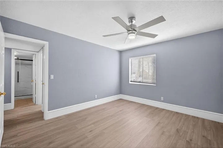 Unfurnished bedroom with a ceiling fan, light wood-style floors, and a textured ceiling