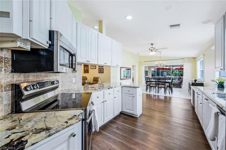 Kitchen with granite countertops, white cabinetry, stainless steel appliances, laminate flooring and tile in the dining area.