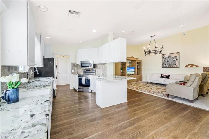 Kitchen with granite countertops, white cabinetry, stainless steel appliances, laminate flooring and a built-in desk area.