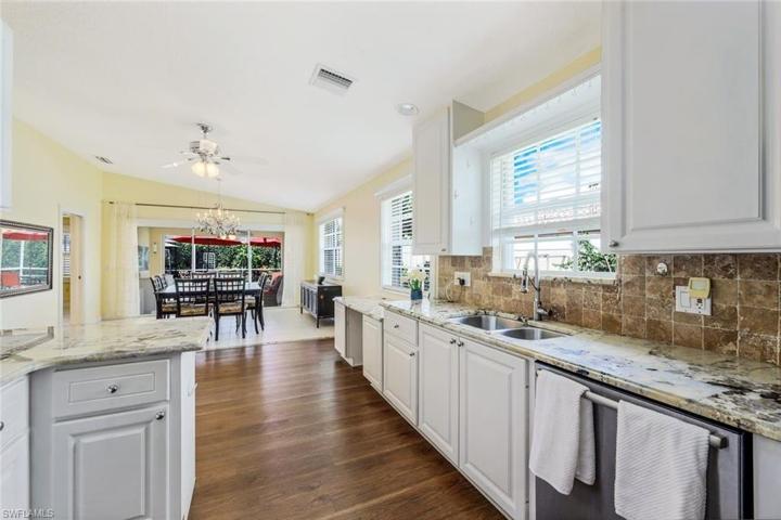 Kitchen with granite countertops, white cabinetry, stainless steel appliances, laminate flooring and tile in the dining area.