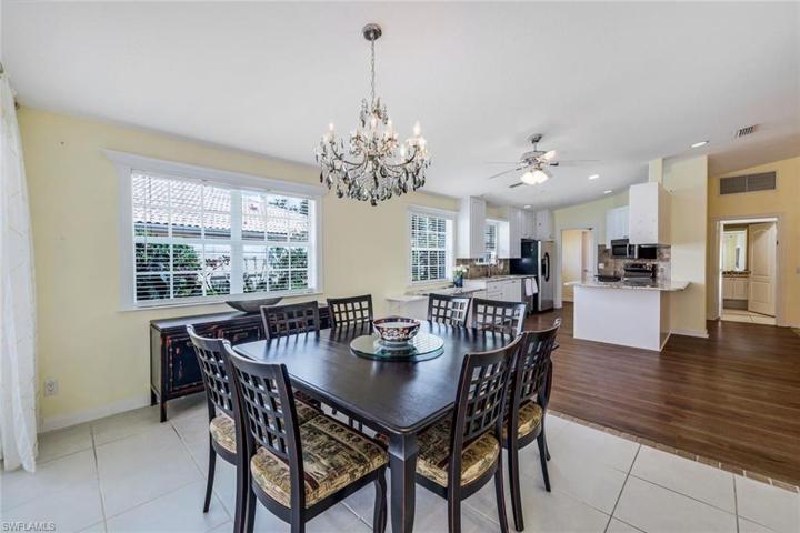 Dining room with chandelier and access to pocket sliding doors out to the lanai and primary suite.