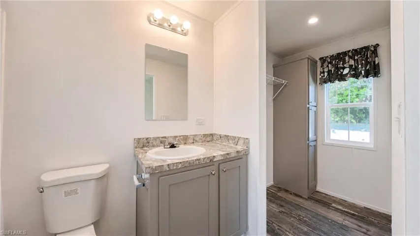 Bathroom vanity with a round sink, light-toned countertop, and gray cabinetry