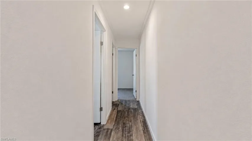 Hallway featuring wood-finish flooring, white painted walls, and recessed lighting