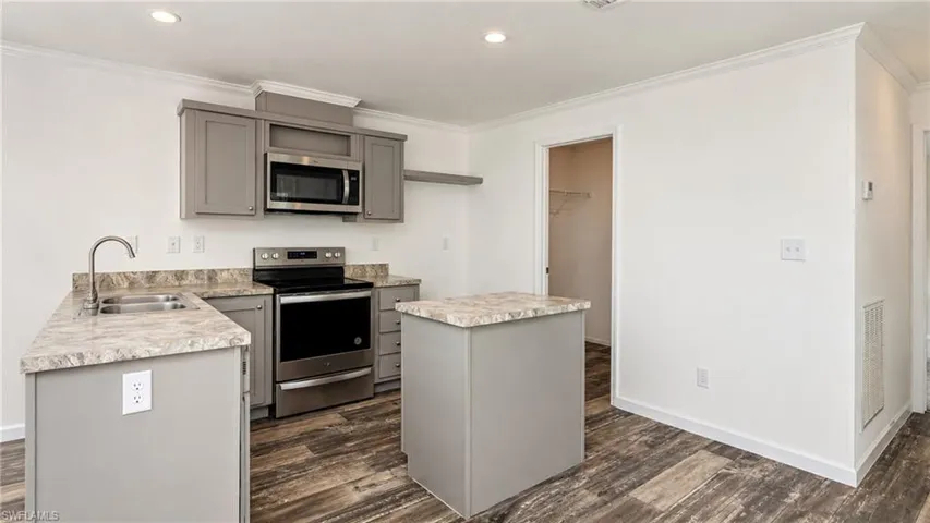 Modern kitchen featuring gray cabinetry, stainless steel appliances, and wood-finish flooring
