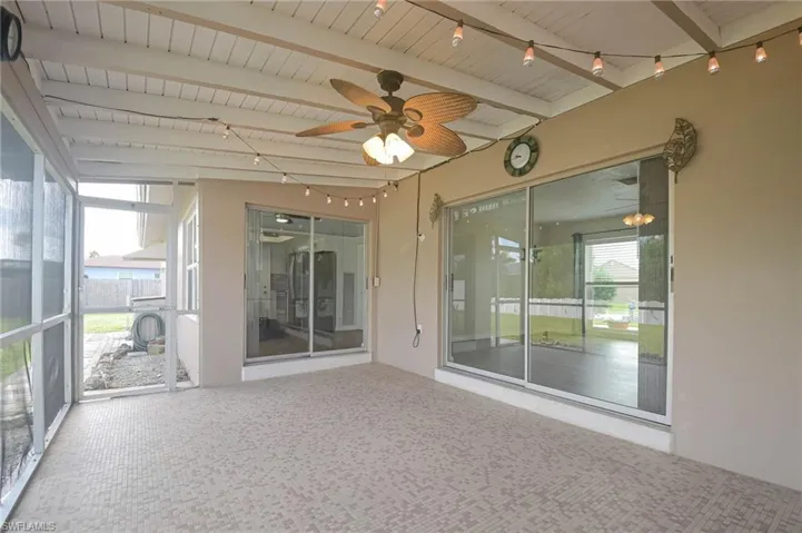 Unfurnished sunroom featuring a healthy amount of sunlight, ceiling fan, and beam ceiling