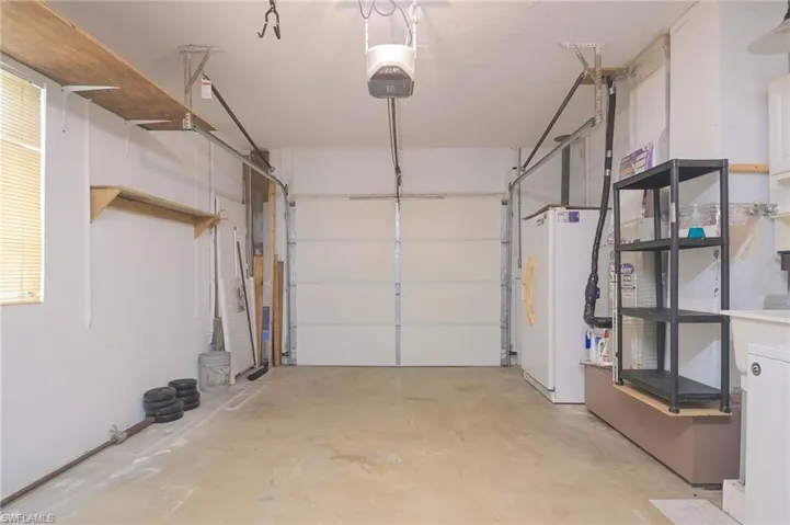 Garage featuring a garage door opener and white fridge