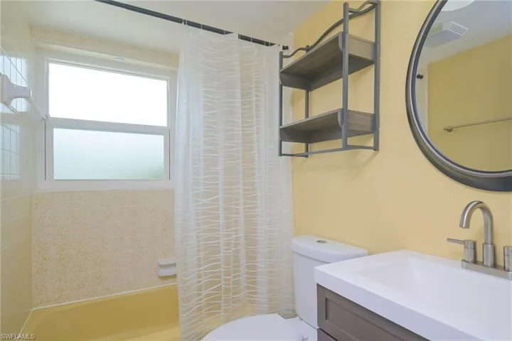 Full bathroom with a healthy amount of sunlight, toilet, shower / tub combo, and vanity