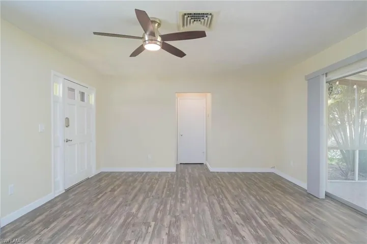 Unfurnished room featuring ceiling fan, a wealth of natural light, and wood-type flooring