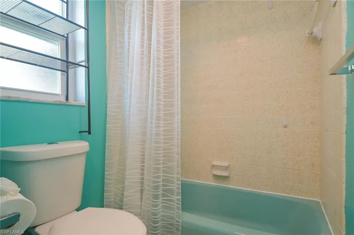 Bathroom featuring toilet, a healthy amount of sunlight, and shower / tub combo
