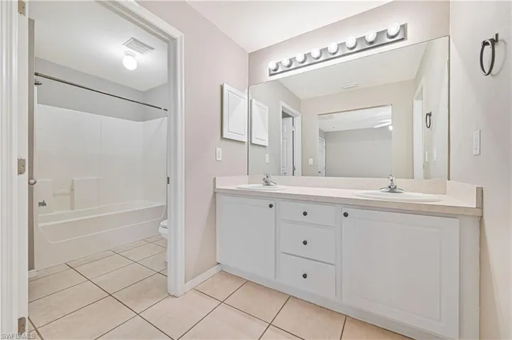 Full bath with tile patterned floors, double vanity, and  shower combination