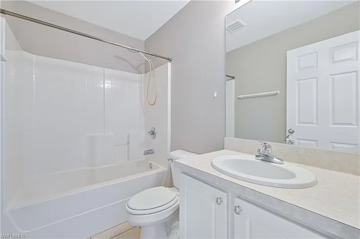 Bathroom with vanity, washtub / shower combination, and tile patterned flooring