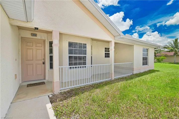 Doorway to property featuring stucco siding and a yard