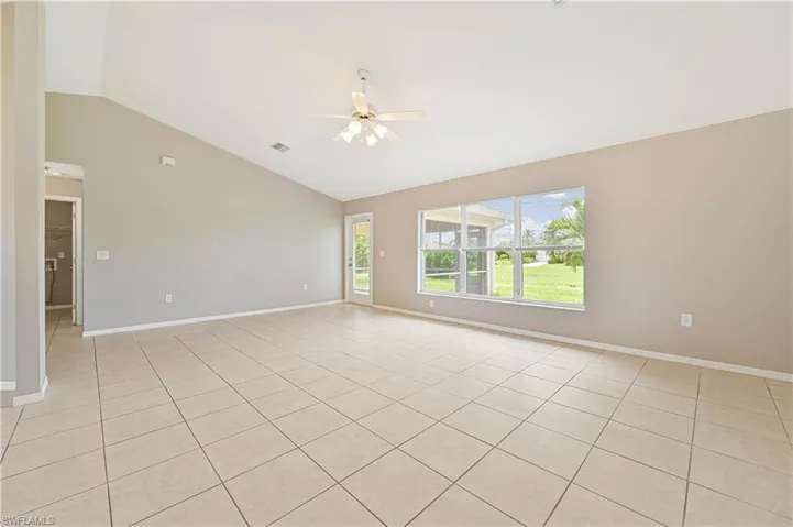 Empty room featuring lofted ceiling, a ceiling fan, and light tile patterned flooring