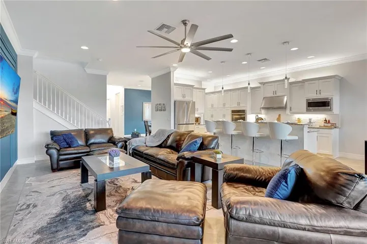 Living area featuring ceiling fan, crown molding, stairway, and recessed lighting