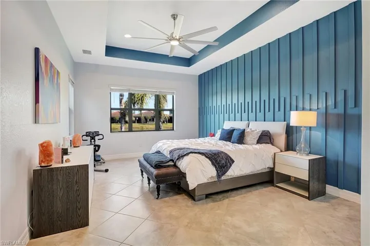 Bedroom featuring tile patterned floors, a tray ceiling, and a ceiling fan