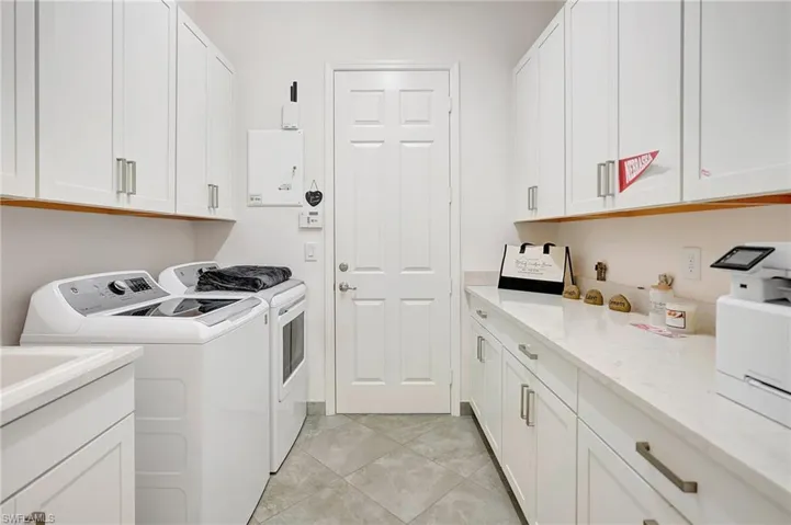 Laundry room featuring washer and clothes dryer, cabinet space, and light tile patterned floors
