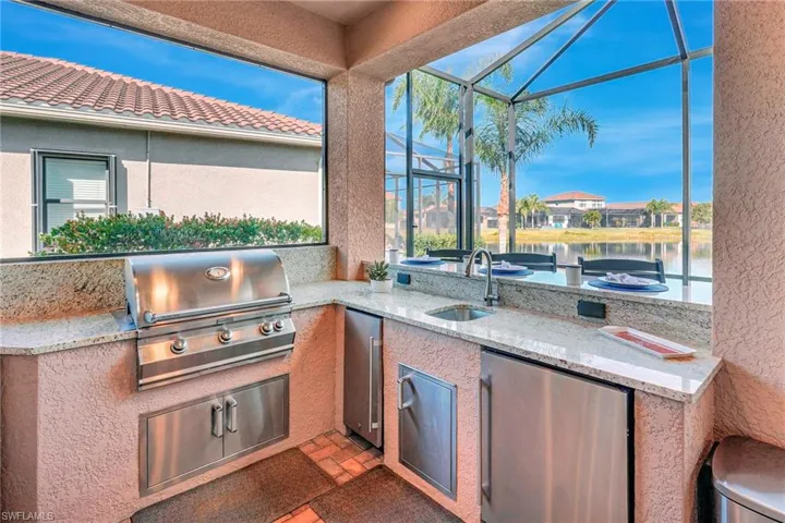 View of patio / terrace featuring a water view, a lanai, and an outdoor kitchen