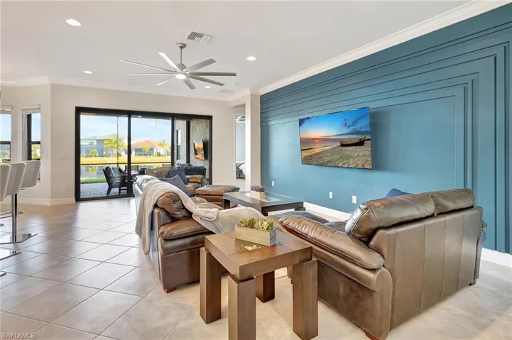 Living room featuring a ceiling fan, recessed lighting, light tile patterned floors, and crown molding