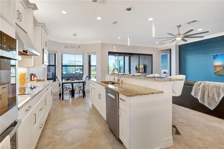 Kitchen featuring appliances with stainless steel finishes, recessed lighting, a kitchen bar, ornamental molding, and an island with sink
