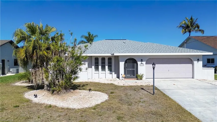 Single story home with concrete driveway, an attached garage, a shingled roof, stucco siding, and a front yard