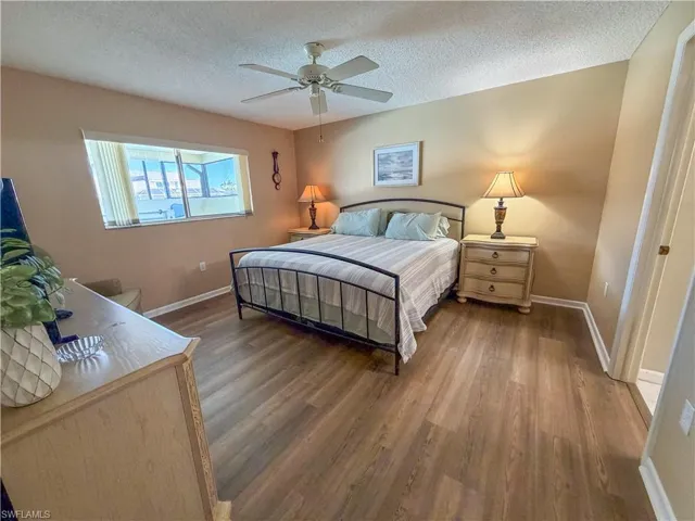 Bedroom with dark wood-style floors, a textured ceiling, and a ceiling fan