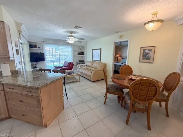 Kitchen featuring built in features, a textured ceiling, a kitchen breakfast bar, dark stone counters, and a peninsula